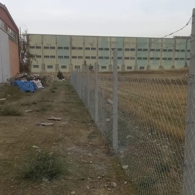 Sanayi parseli sınırında beton direkli galvaniz tel örgü, üstte dikenli tel